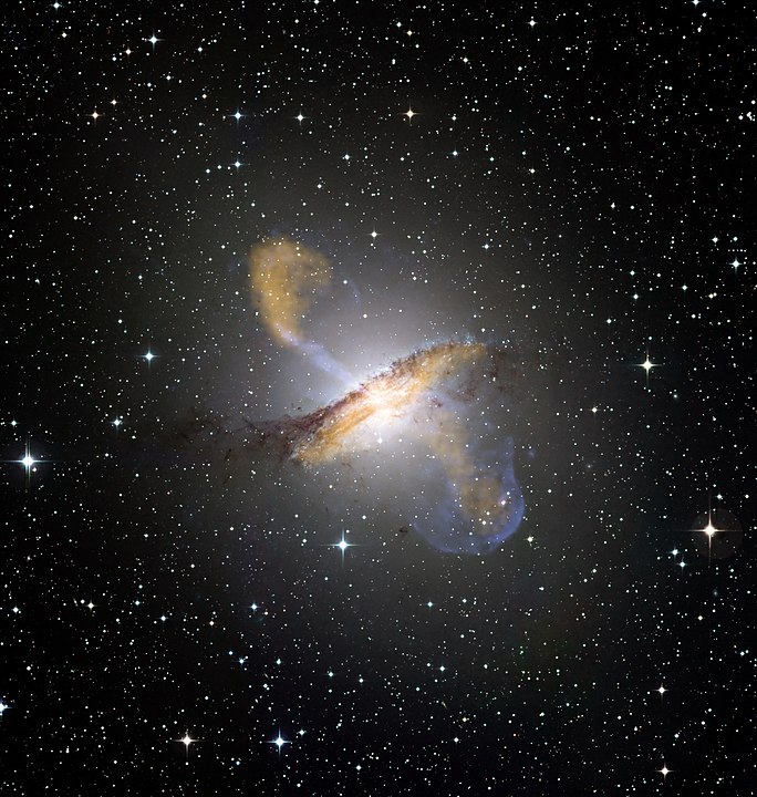 Colour composite image of Centaurus A, revealing the lobes and jets emanating from the active galaxy’s central black hole. This is a composite of images obtained with three instruments, operating at very different wavelengths. The 870-micron submillimetre data, from LABOCA on APEX, are shown in orange. X-ray data from the Chandra X-ray Observatory are shown in blue. Visible light data from the Wide Field Imager (WFI) on the MPG/ESO 2.2 m telescope located at La Silla, Chile, show the stars and the galaxy’s characteristic dust lane in close to "true colour".