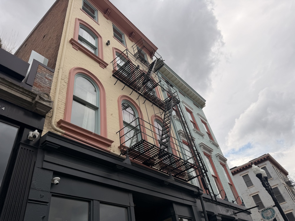 An upward angle on pastel-trimmed buildings and fire escapes near Findlay Market.