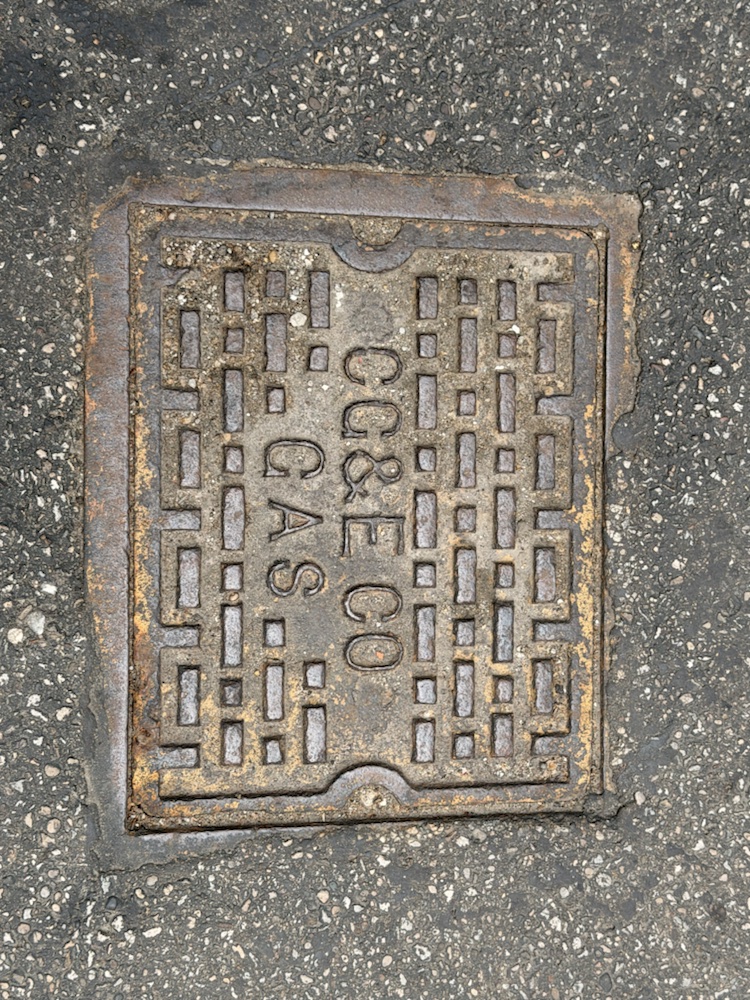 A rectangular utility cover stamped CGC and Co cast into the pavement.