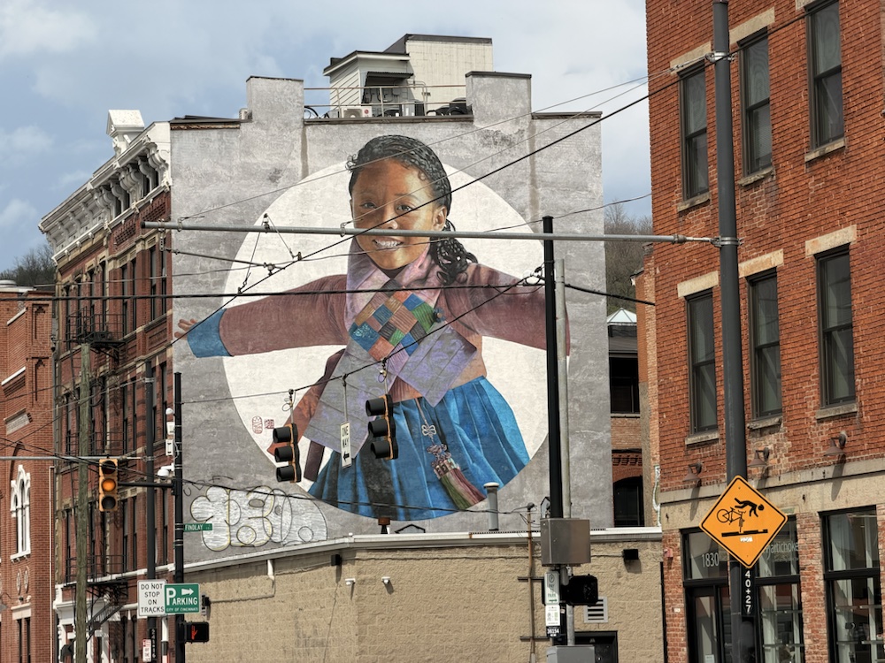 A large portrait mural of a young person on a wall near Findlay Market.